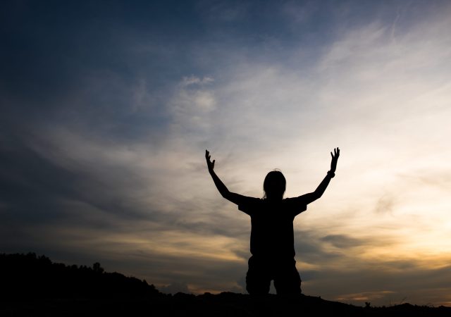Silhouette of woman praying with god